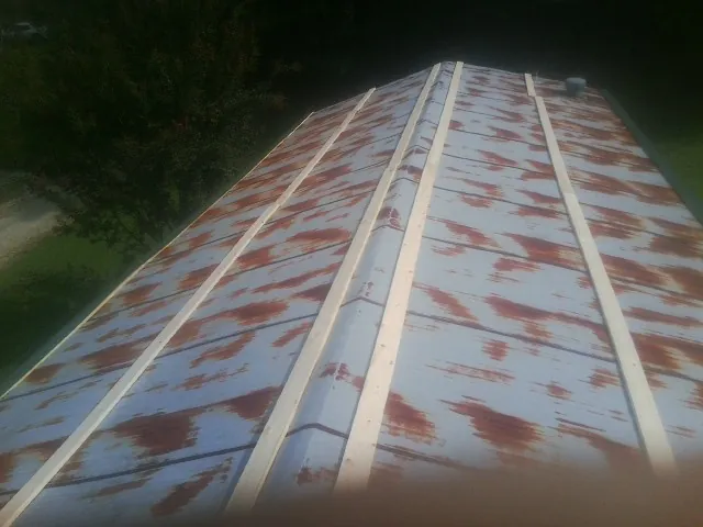 Rusted metal roof panels with new wood purlins before replacement — Storm Damage Roof Repair in Loveland by Roofing Brothers