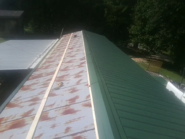 Old rusted panels beside newly installed green metal roofing — Wind Damage Roof Repair by Roofing Brothers in Loveland