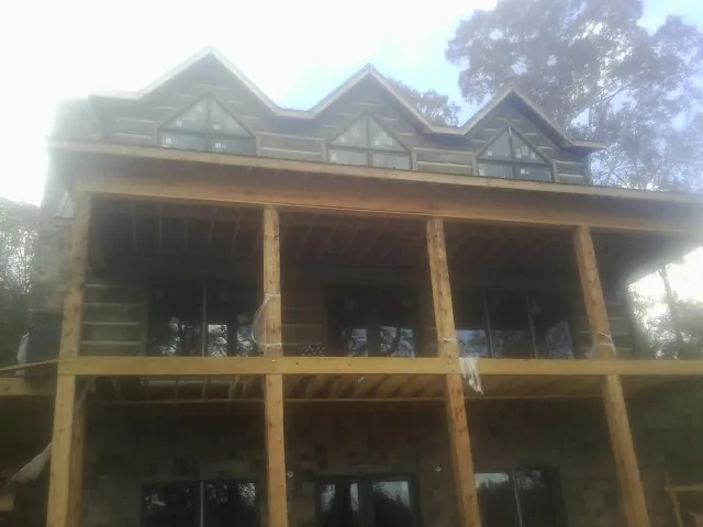 Dormers and porch framing on a large log home under construction — Roof Coating work by our crew in Loveland
