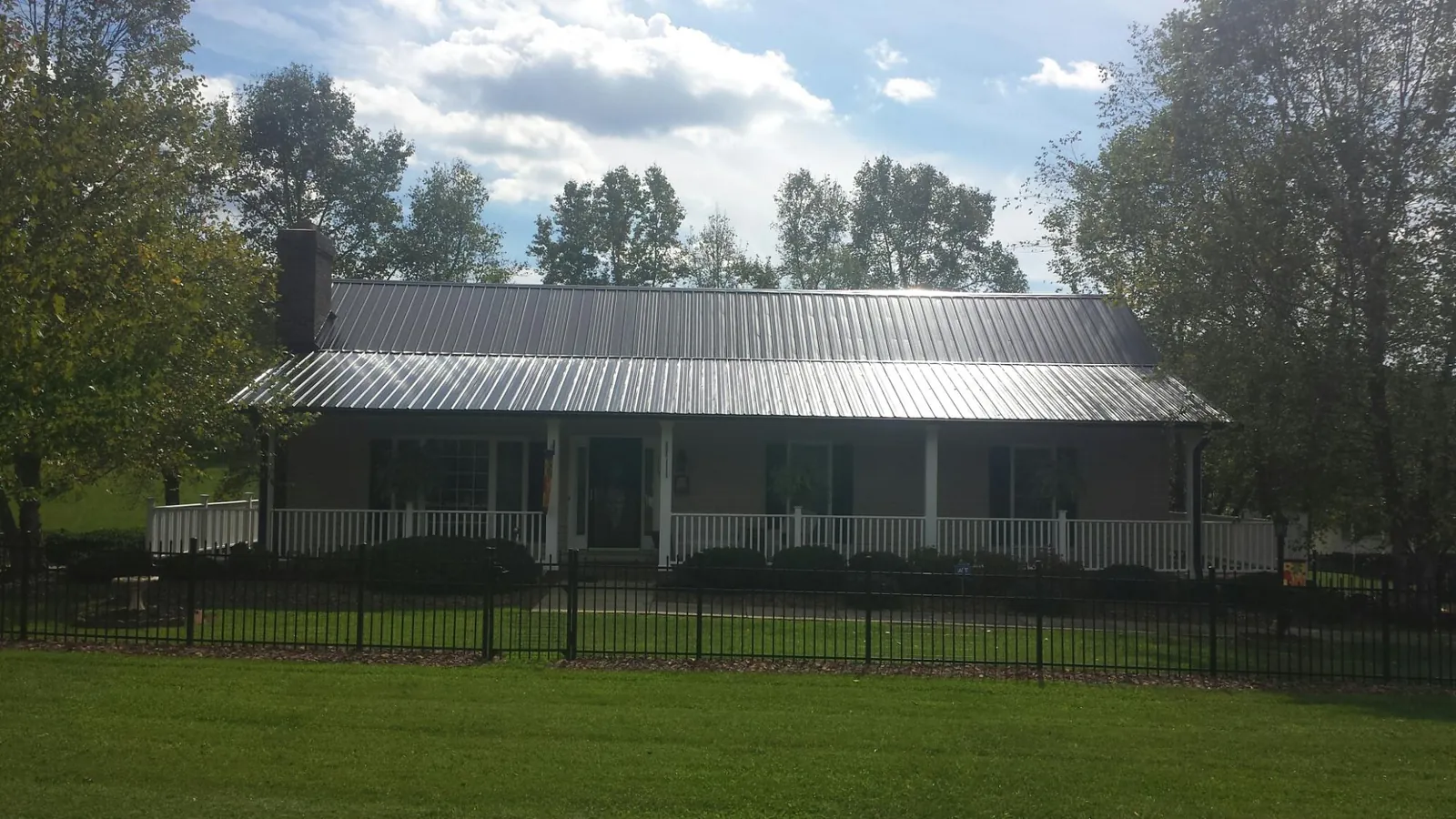 Gray metal roof on a brick ranch with a full width front porch — Gutter Guard Installation work by our crew in Loveland
