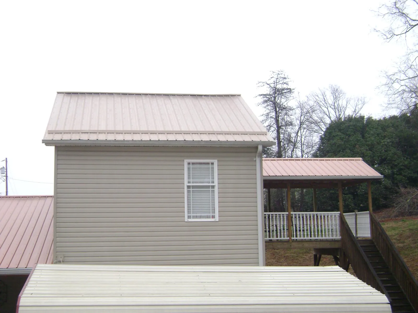 Tan metal roofs on a two story addition and attached porch, from a Roof Replacement job in Loveland