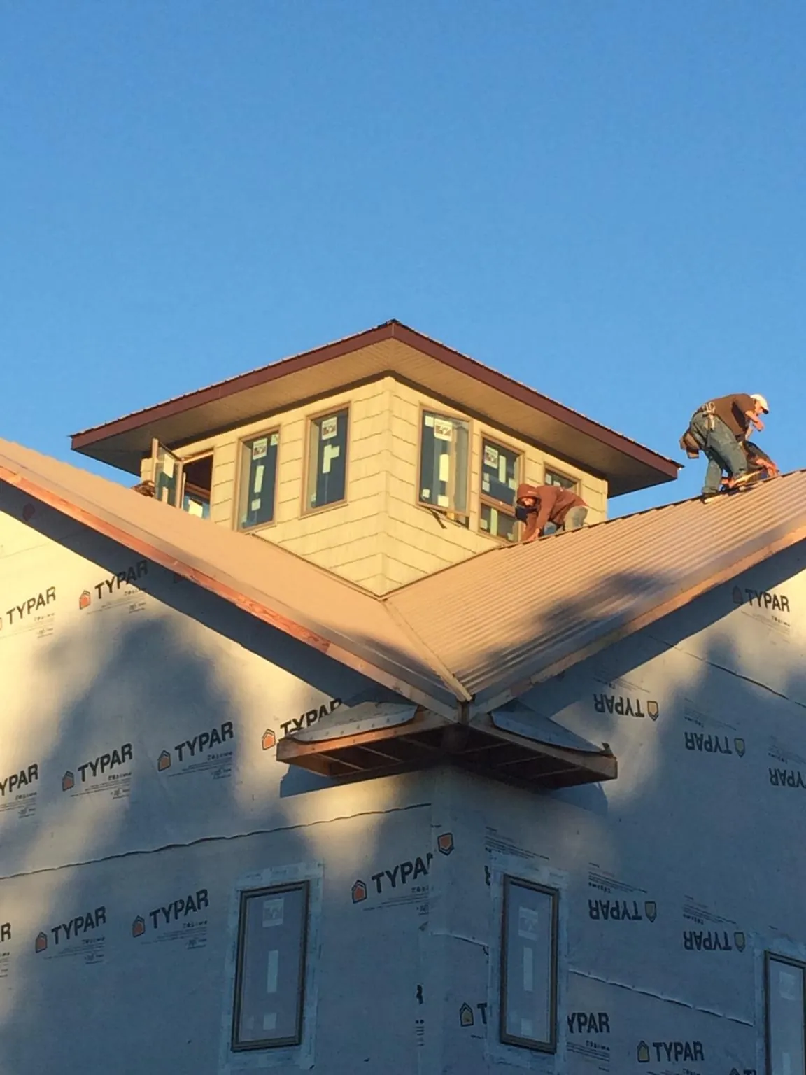 Roofers working around a rooftop cupola on a new metal roof at sunset — Roof Waterproofing in Loveland by Roofing Brothers